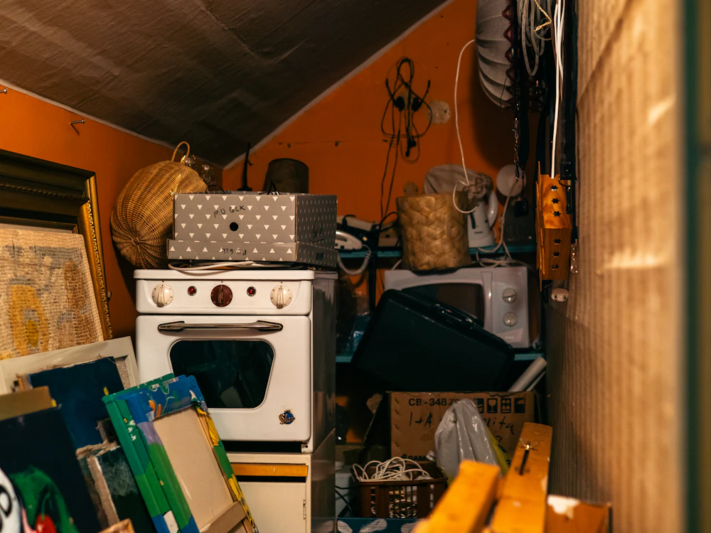 A room filled with clutter, furniture and cardboard boxes