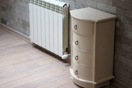A white cabinet next to a brick wall