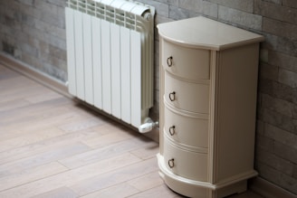 A white cabinet next to a brick wall