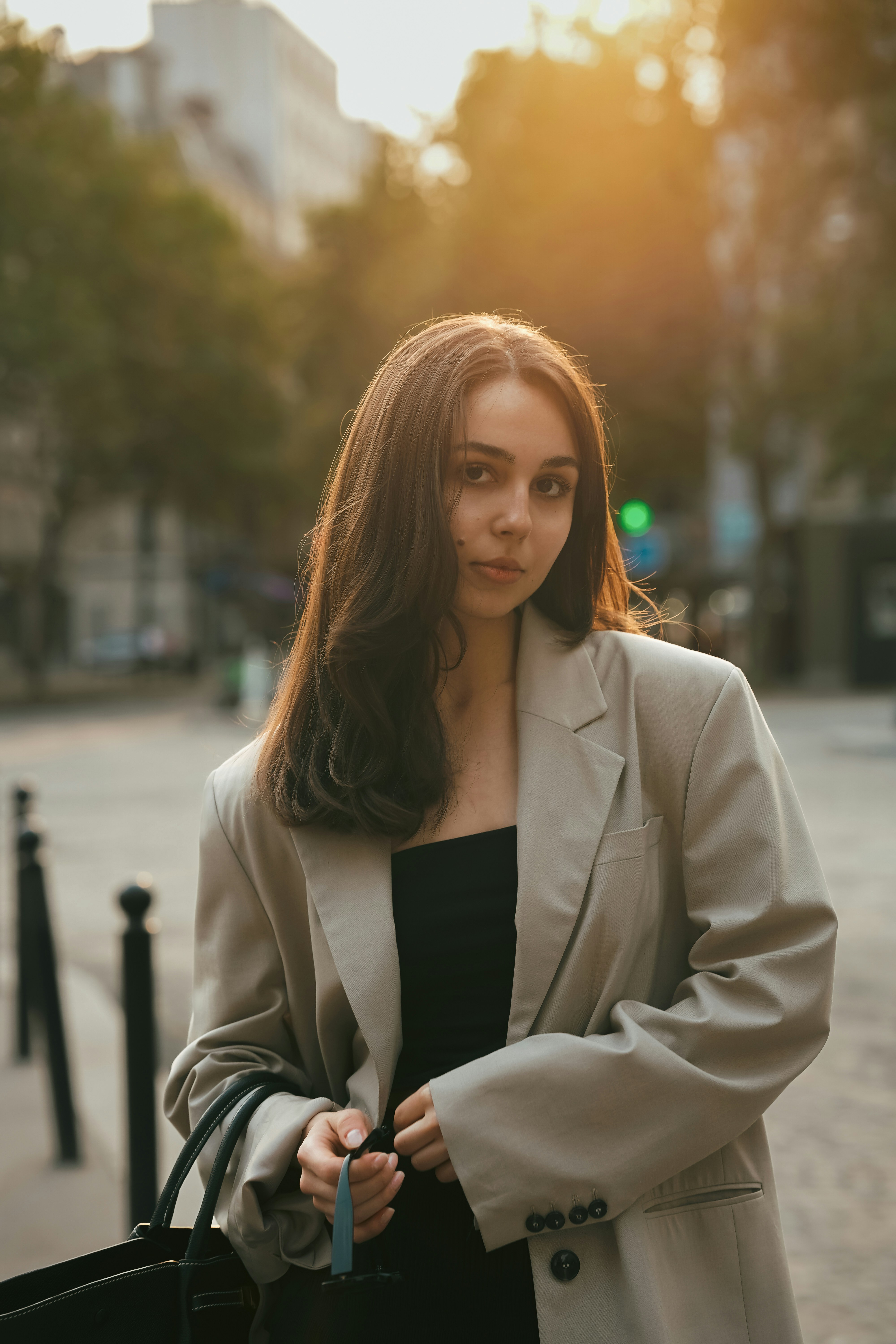 Model in oversized beige jacket walking on empty city street at golden hour, long shadows, relaxed stance