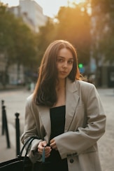 A woman standing on a street holding a black bag