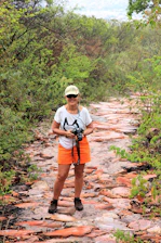 A woman standing on a rocky path with a camera