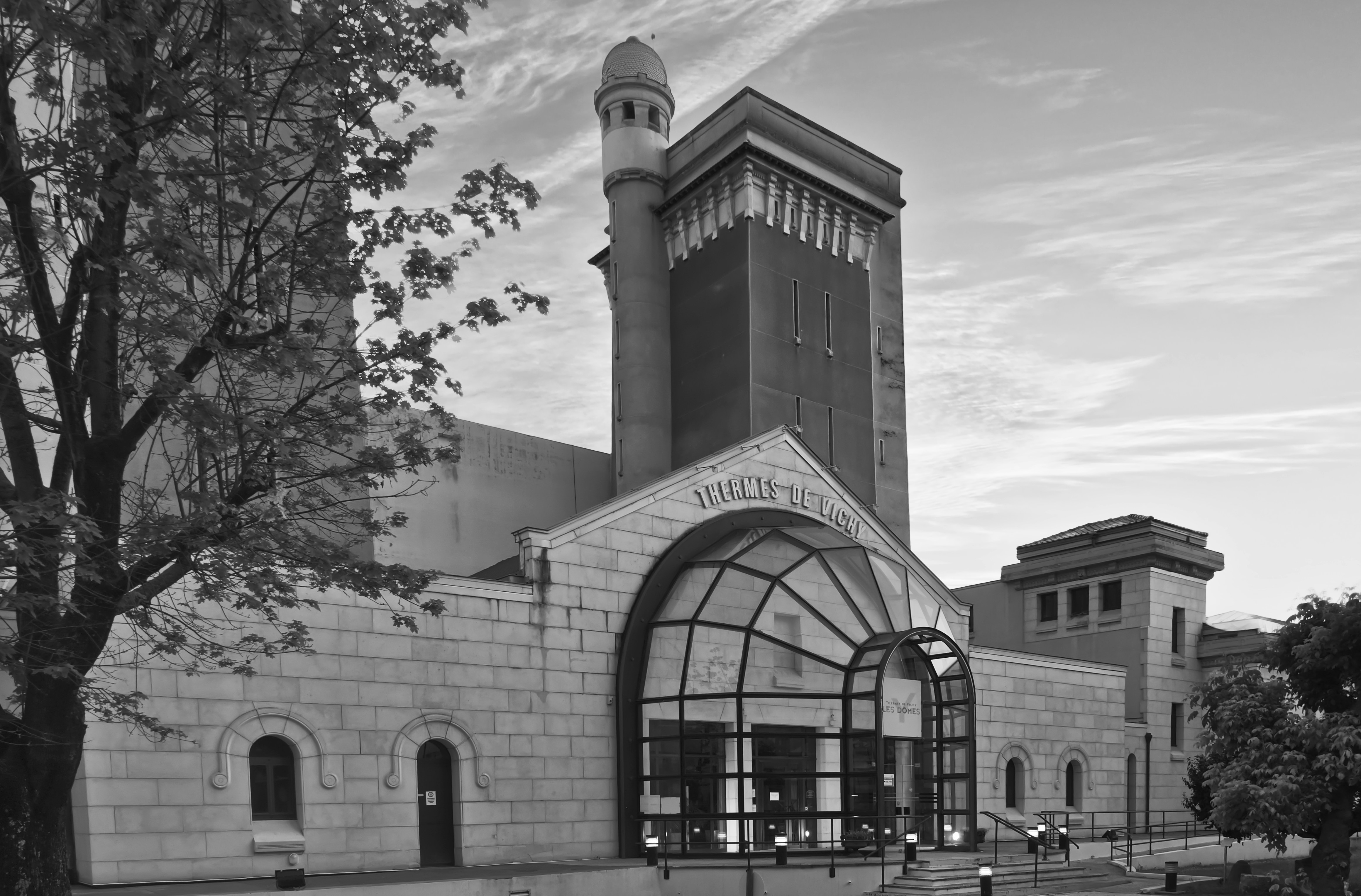 Cette entrée des Thermes des Dômes de Vichy est construite en 1934. Le bâtiment central et plusieurs annexes dont une aile, aujourd’hui encore surplombée par deux tours de style néo-byzantin, qui étaient utilisées comme réservoirs d’eau de source. L’ensemble du site des Dômes est commandé en 1900 par la Compagnie Fermière. Le centre thermal des Dômes a été construit en 3 ans sous la conduite des architectes Charles Lecoeur et Lucien Woog assistés de l'architecte de la Compagnie Fermière Gustave Simon. L'inauguration a eu lieu le 31 mai 1903.