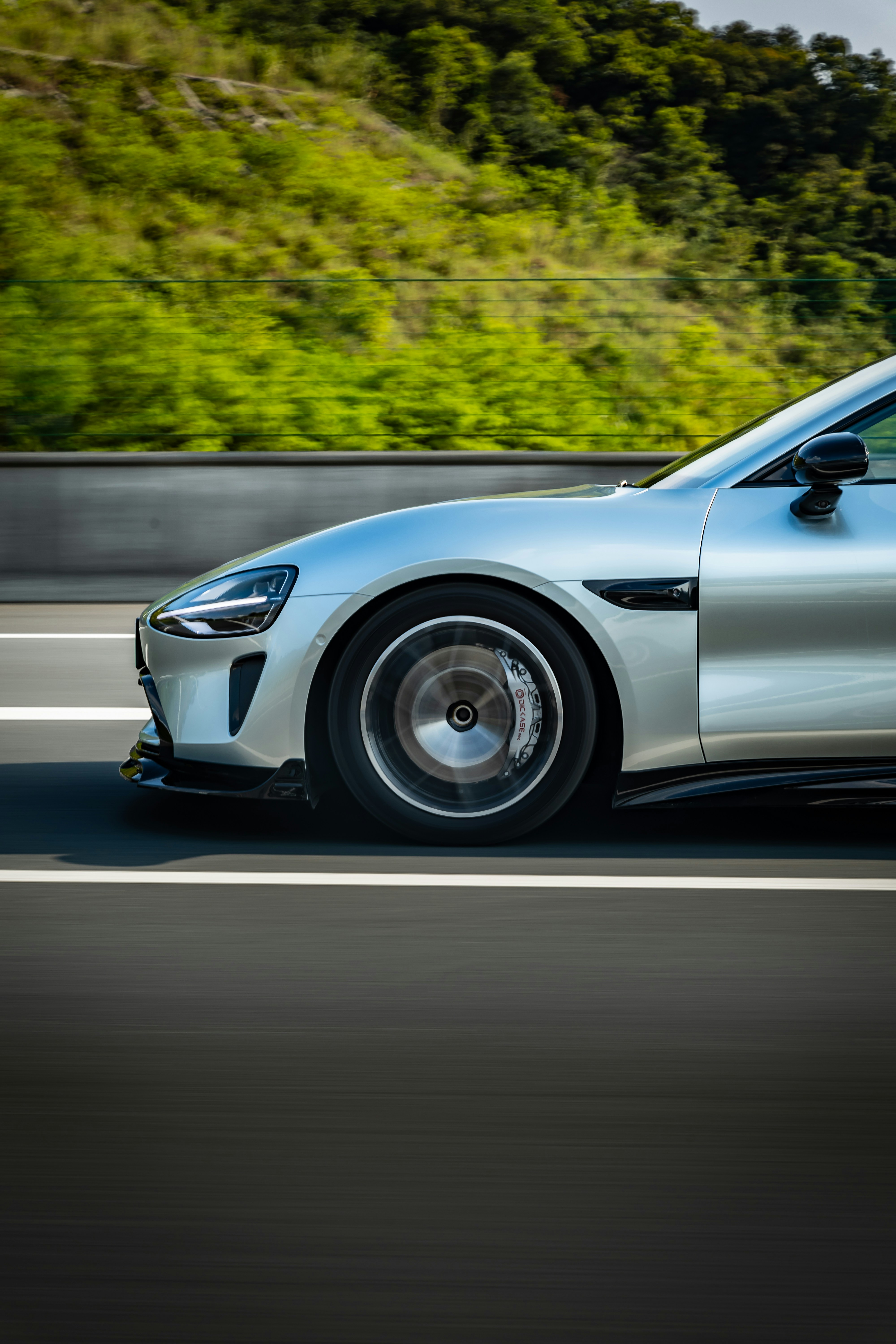 A silver sports car driving down the road