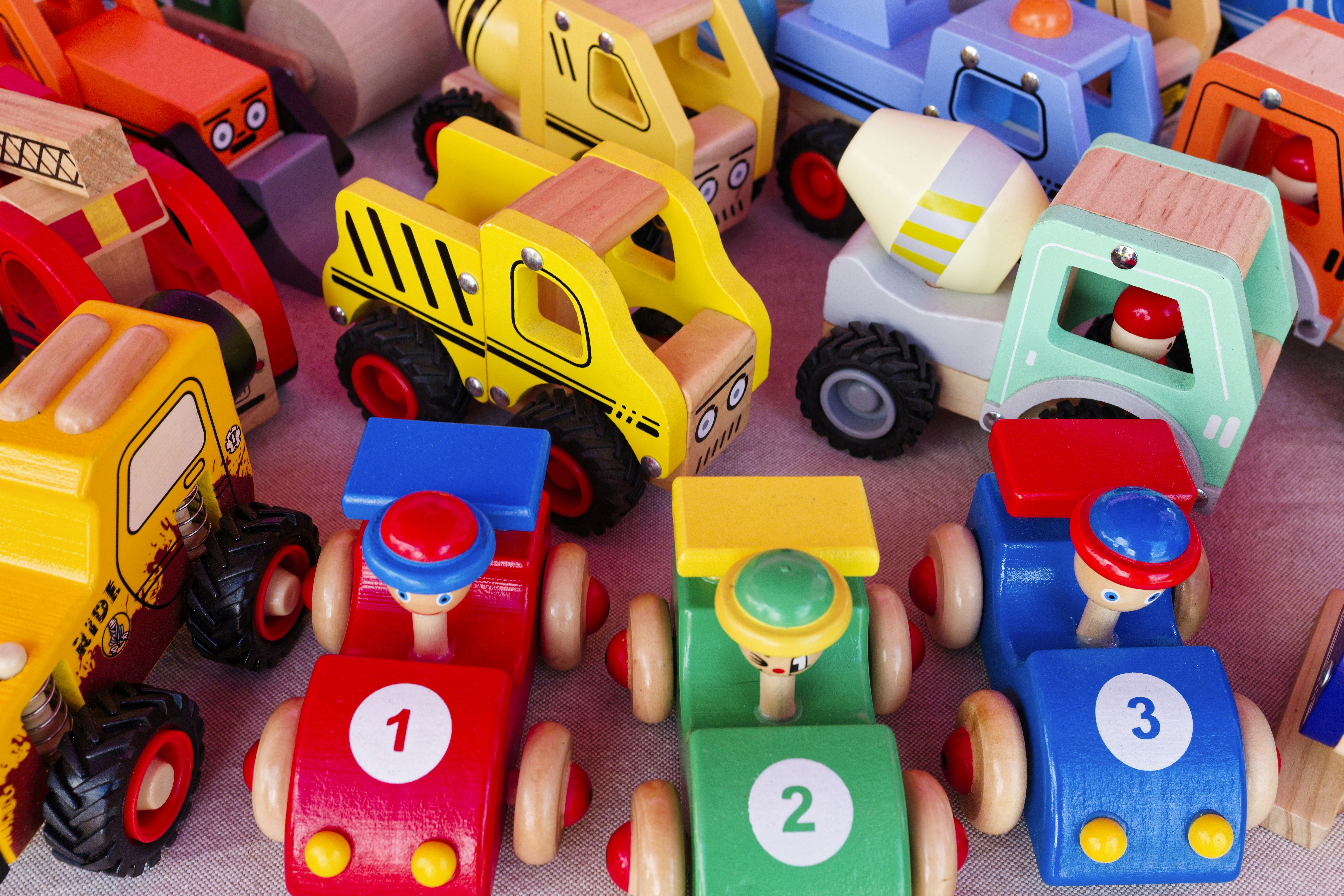 Colorful wooden toy vehicles arranged on a table, showcasing a variety of designs and vibrant colors for children's playtime enjoyment - A collection of colorful wooden toy vehicles is neatly arranged on a table