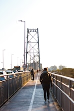 A man walking across a bridge over a river