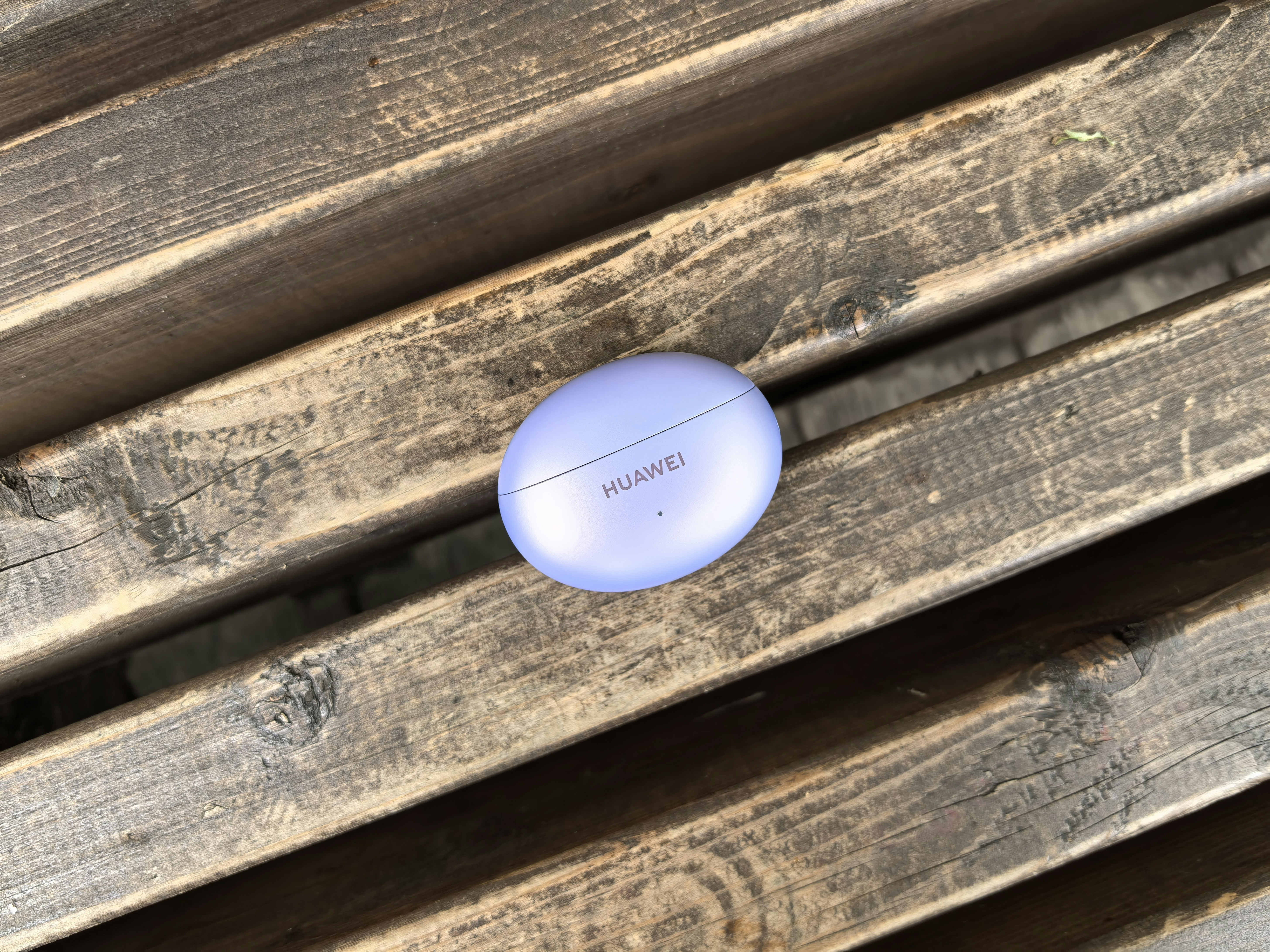 A blue frisbee sitting on top of a wooden bench
