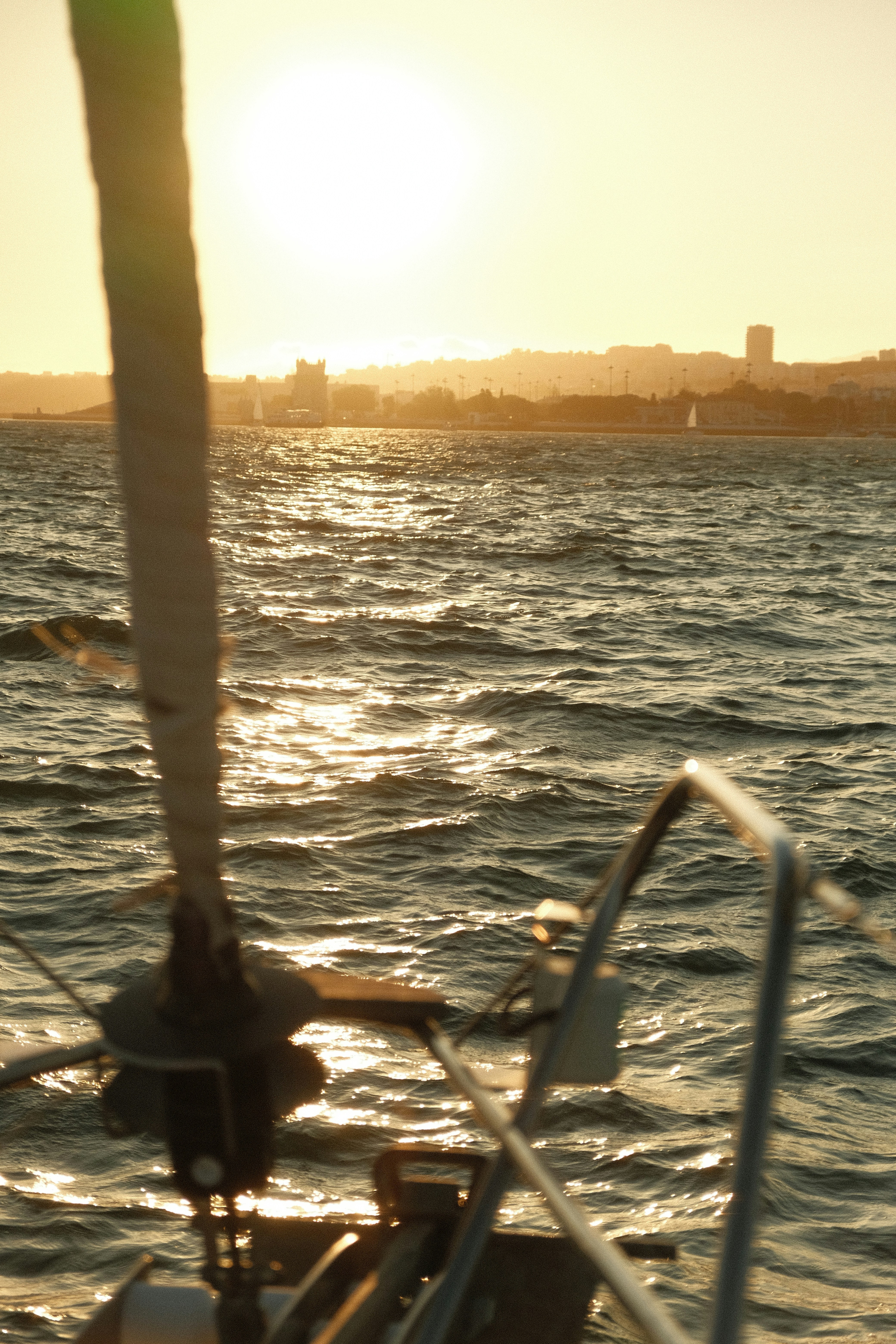 A sailboat in the water with the sun in the background