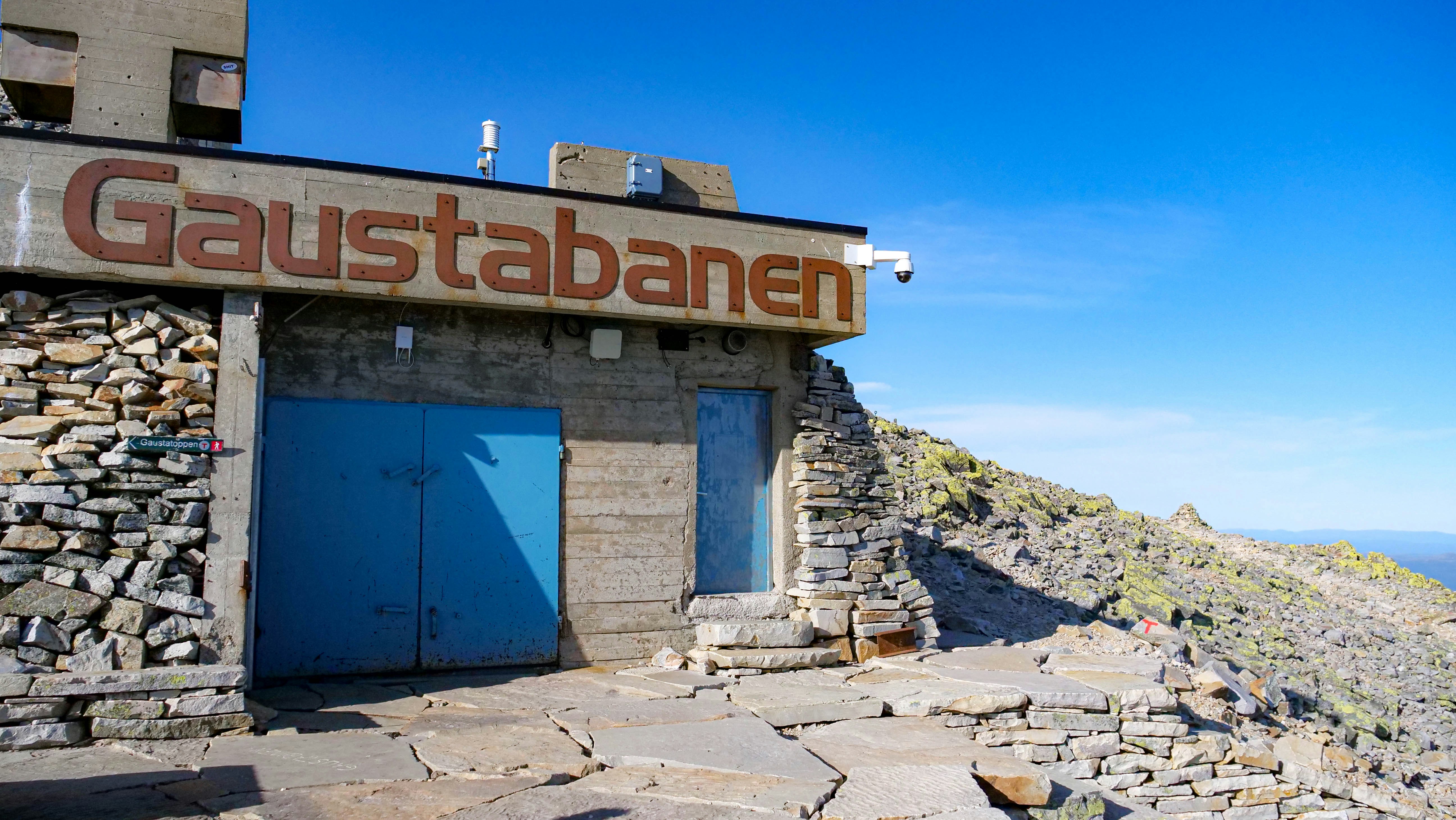 A stone building with a blue door on top of a mountain