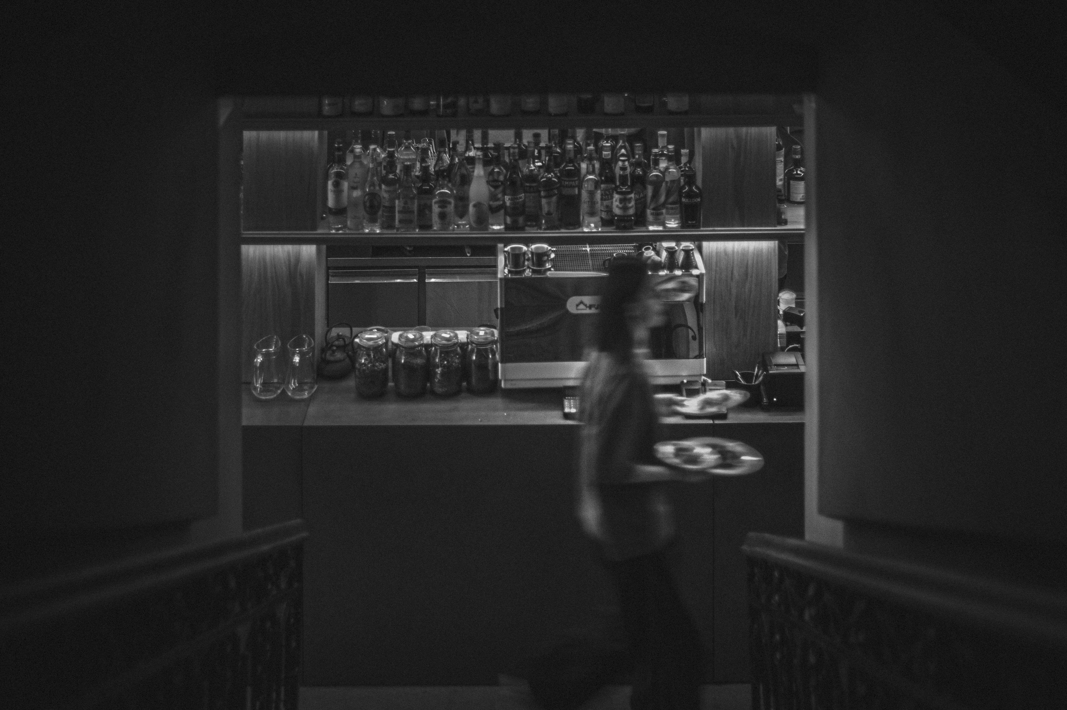 A waitress in front of a bar and a coffee machine.