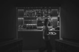 A man walking down a dark hallway next to a bar