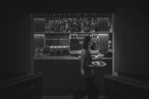 A man walking down a dark hallway next to a bar