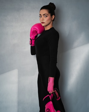 A woman in a black dress and pink boxing gloves
