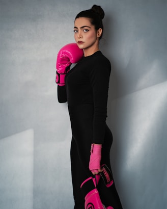 A woman in a black dress and pink boxing gloves