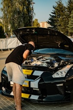 A man standing next to a black sports car