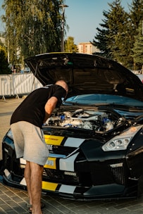 A man standing next to a black sports car