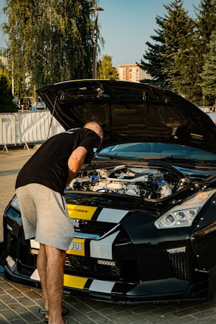 A man standing next to a black sports car