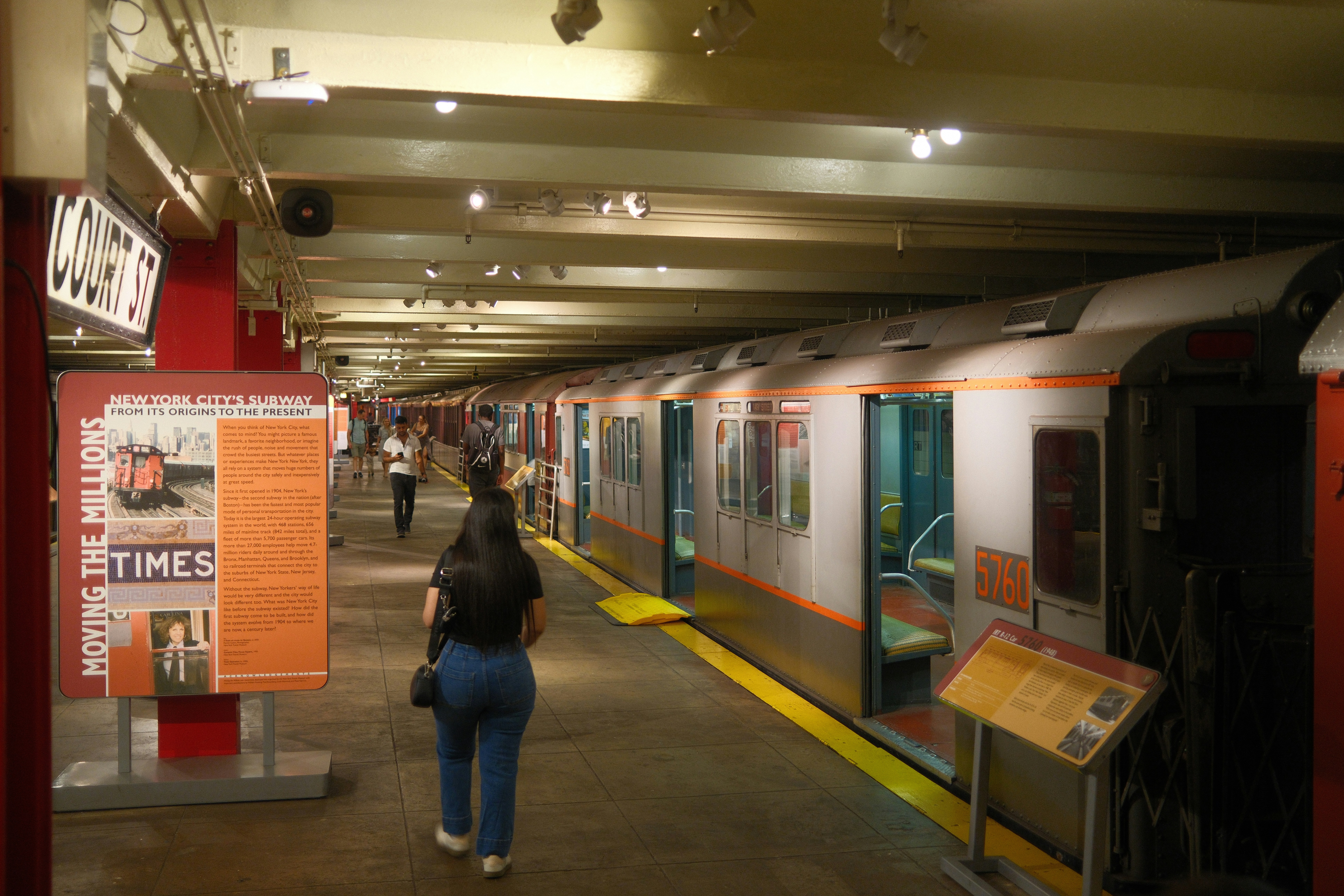 A woman walking down a hallway next to a train