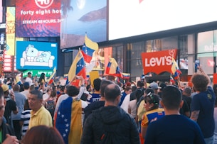 A crowd of people walking down a street next to tall buildings