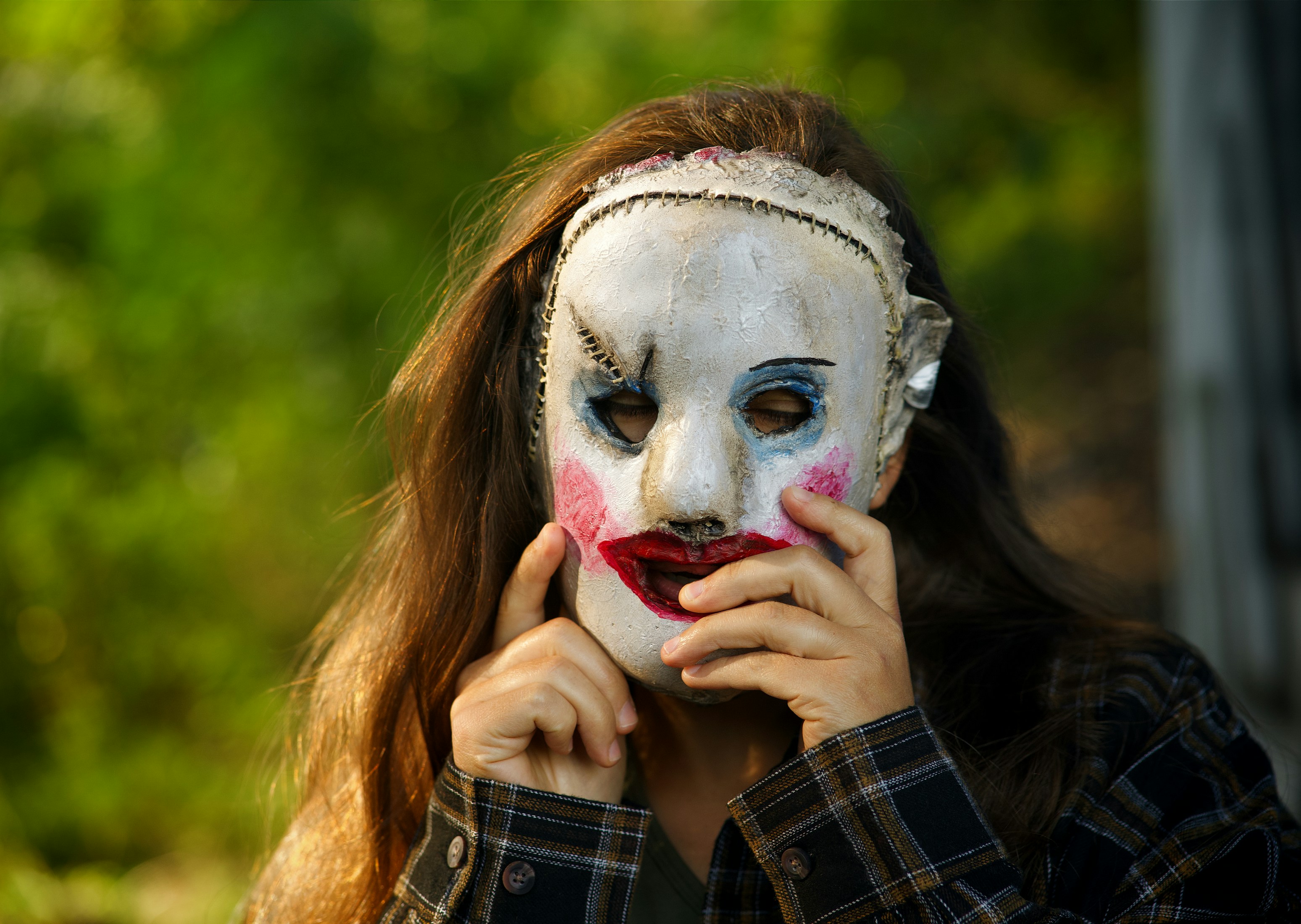 A woman wearing a white mask with a red nose