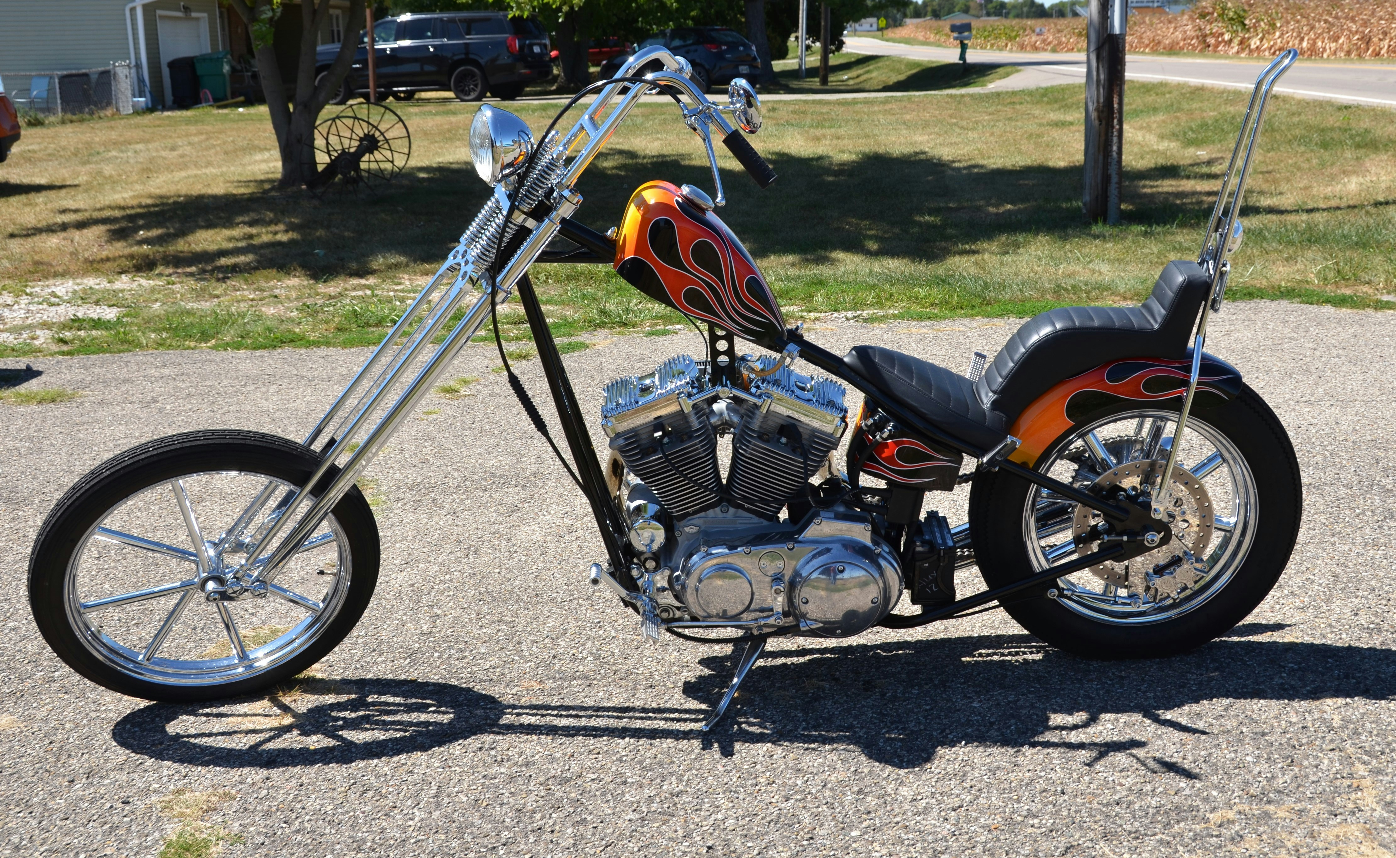 Custom chopper motorcycle parked on an asphalt driveway.