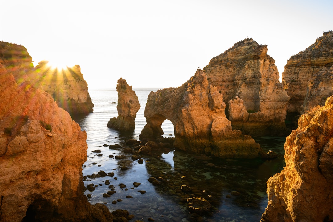 The sun shines through the rocks near the ocean, A few more sunrises like this will make a morning person out of me...