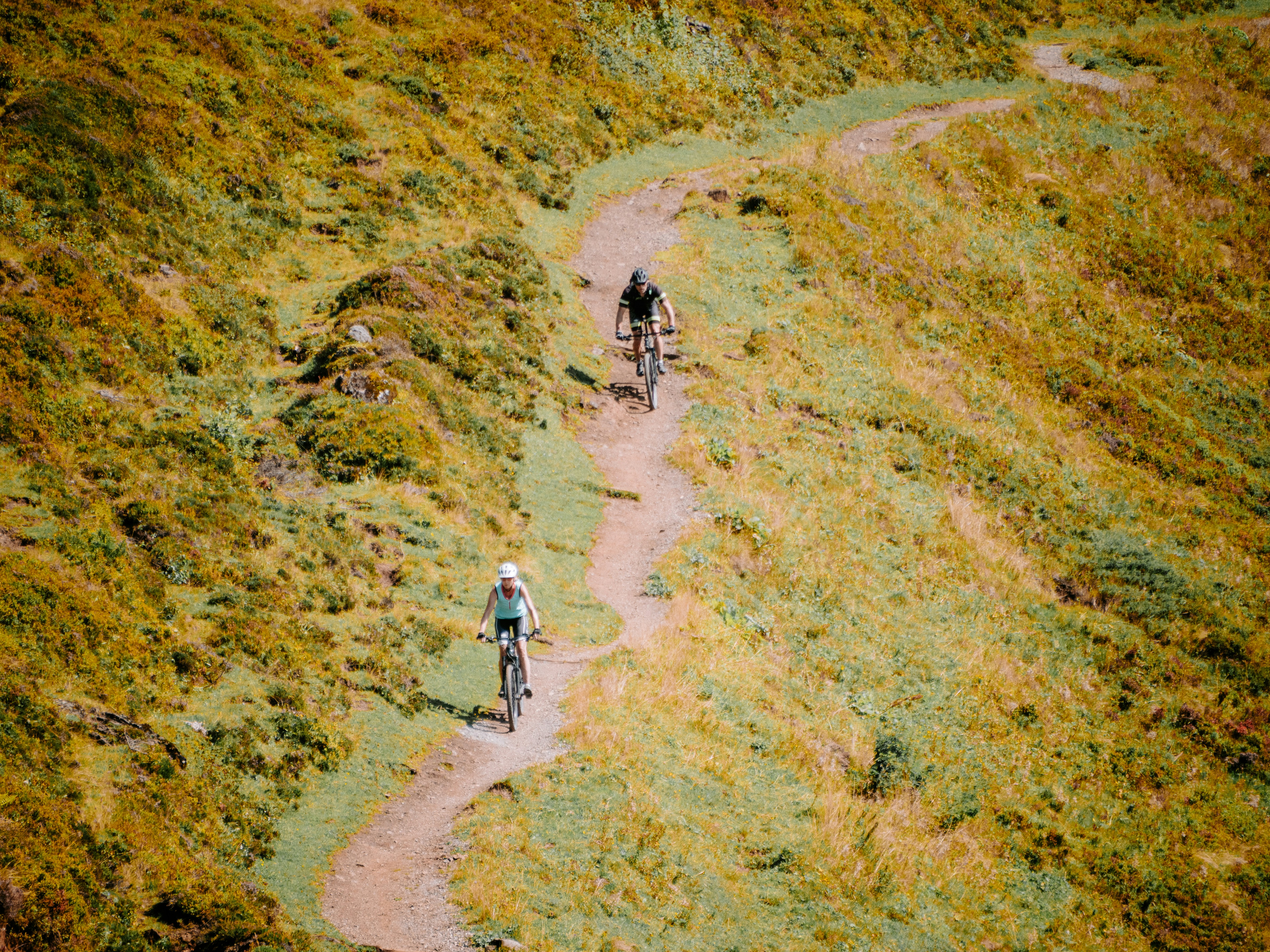 A couple of people riding bikes down a dirt road