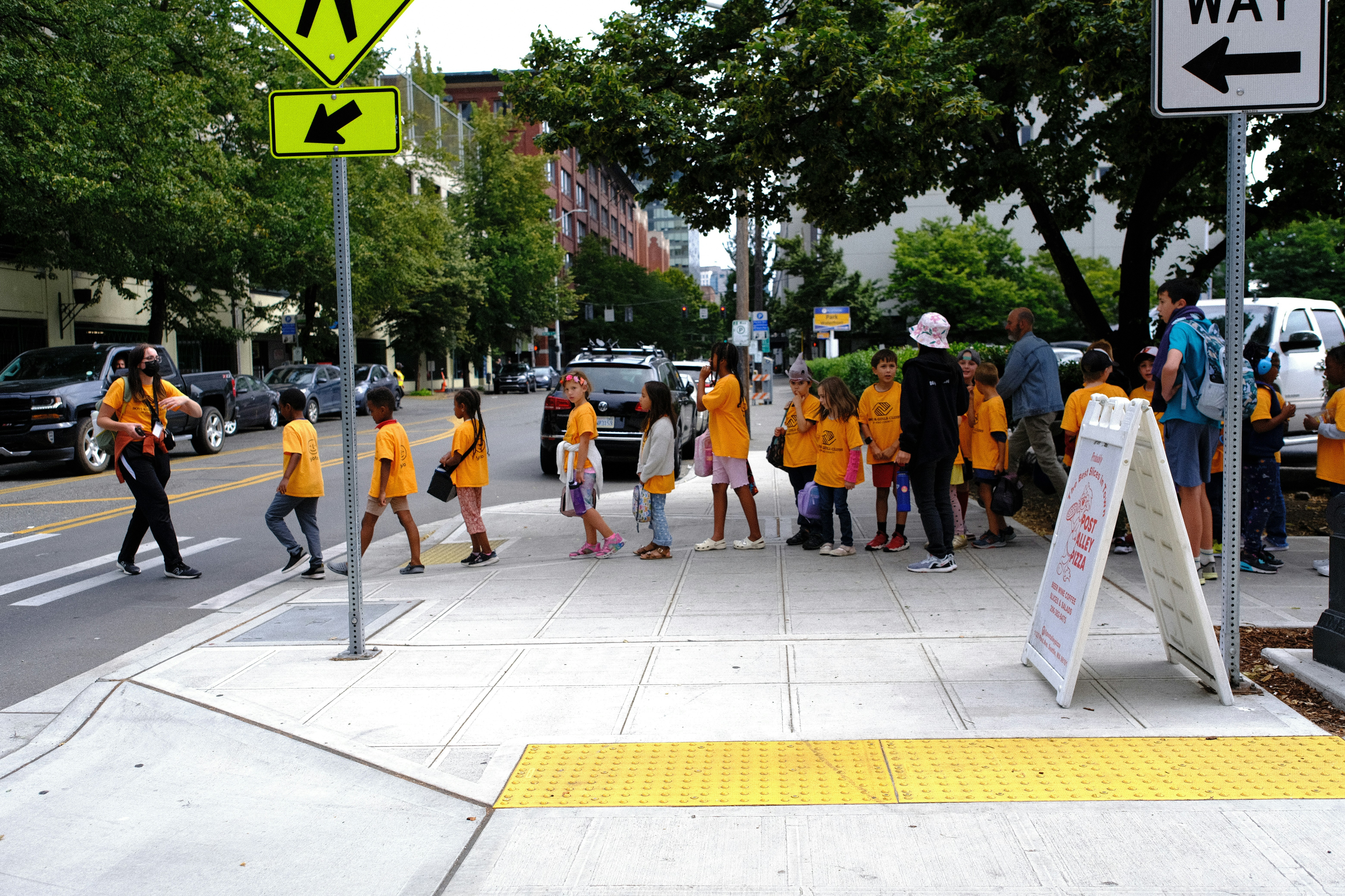 A group of people in orange shirts walking down a street