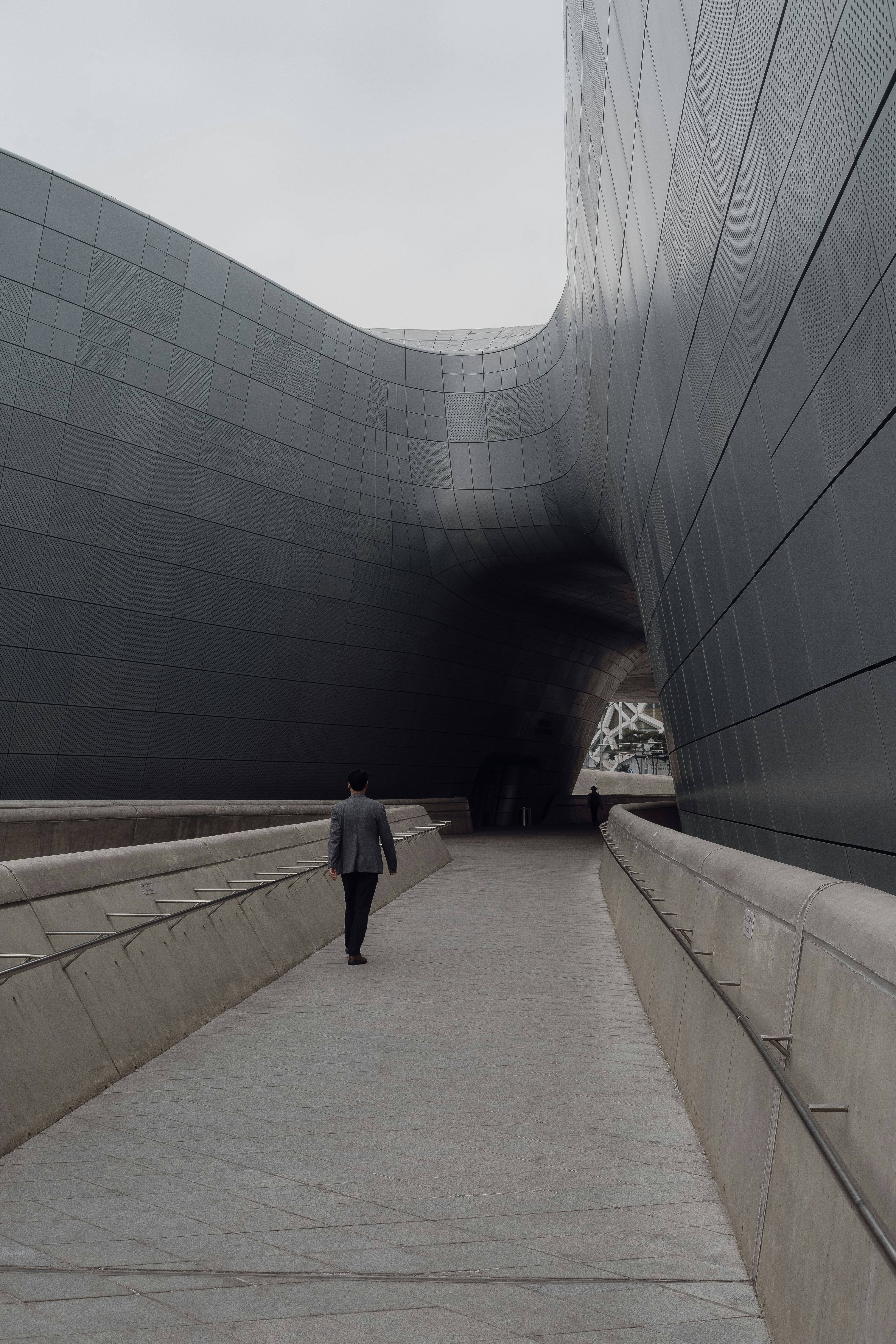 A man walking down a walkway next to a large building