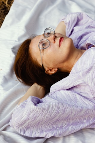 A woman with glasses laying on a blanket