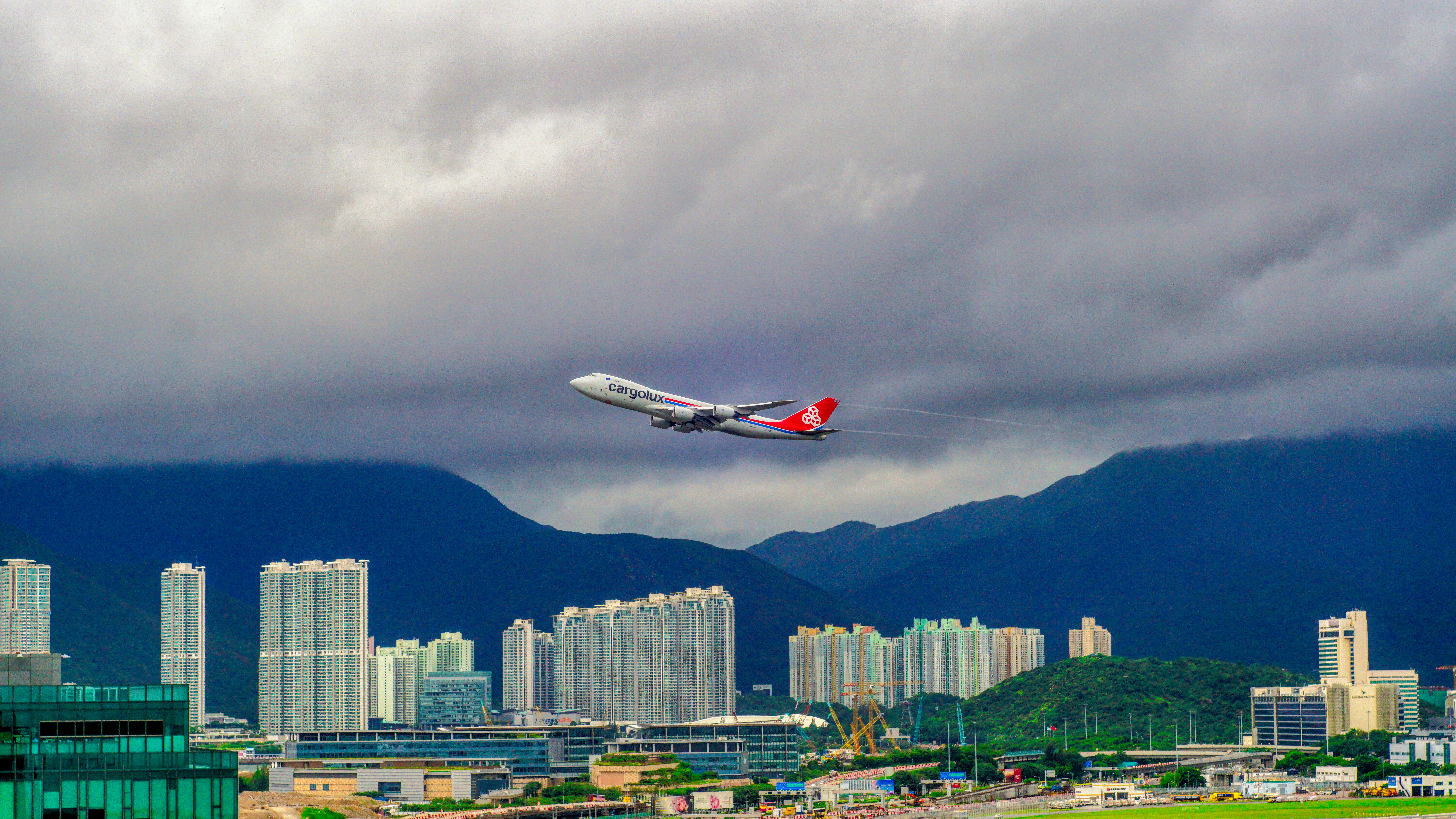 An airplane flying over a city under a cloudy sky