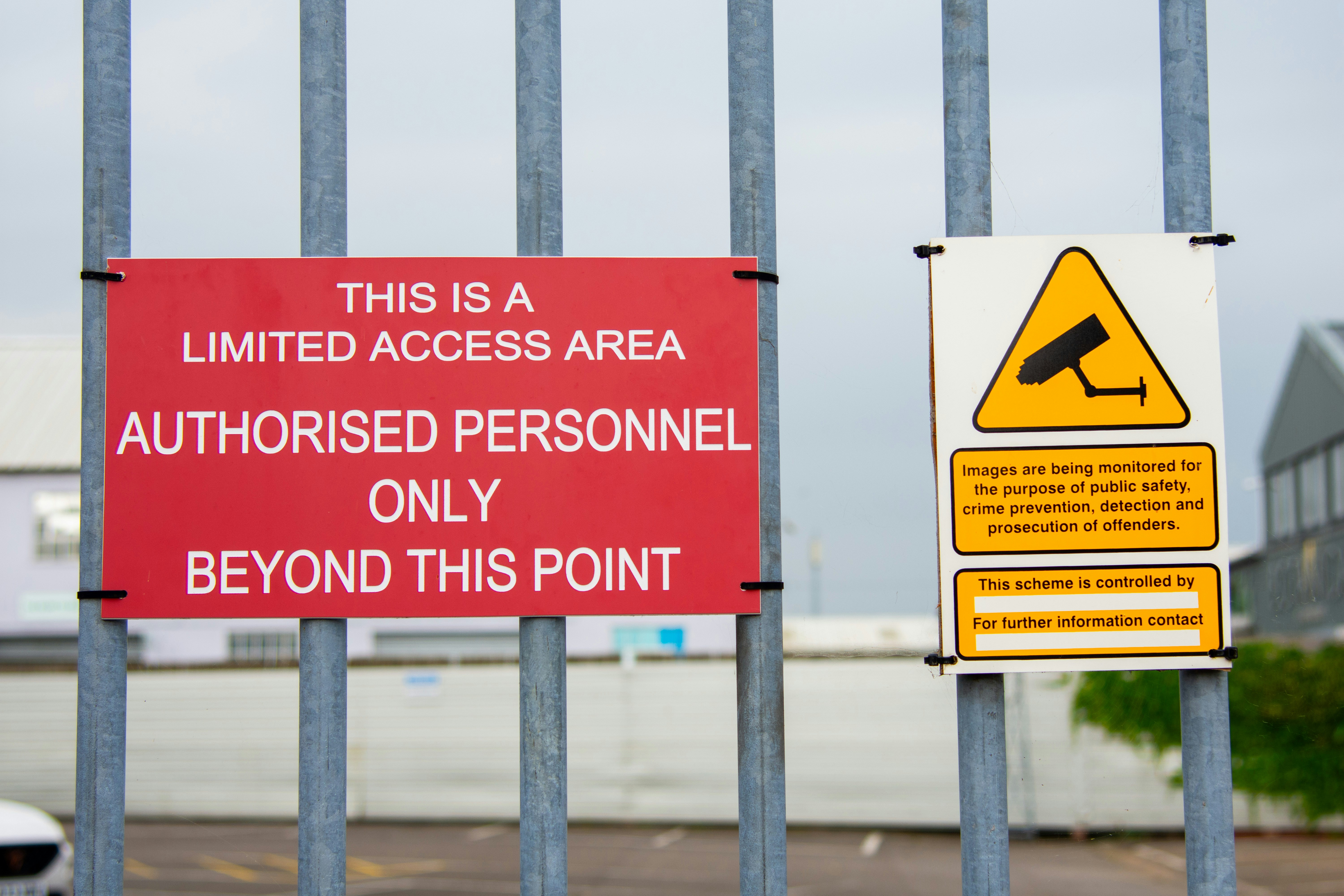 A red sign sitting on the side of a metal fence