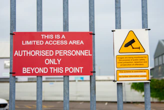 A red sign sitting on the side of a metal fence