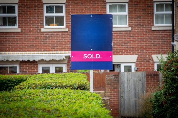 A sold real estate sign in front of a residential building, representing closed transactions rather than pending contracts