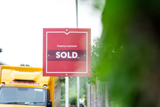 A red sold sign sitting on the side of a road