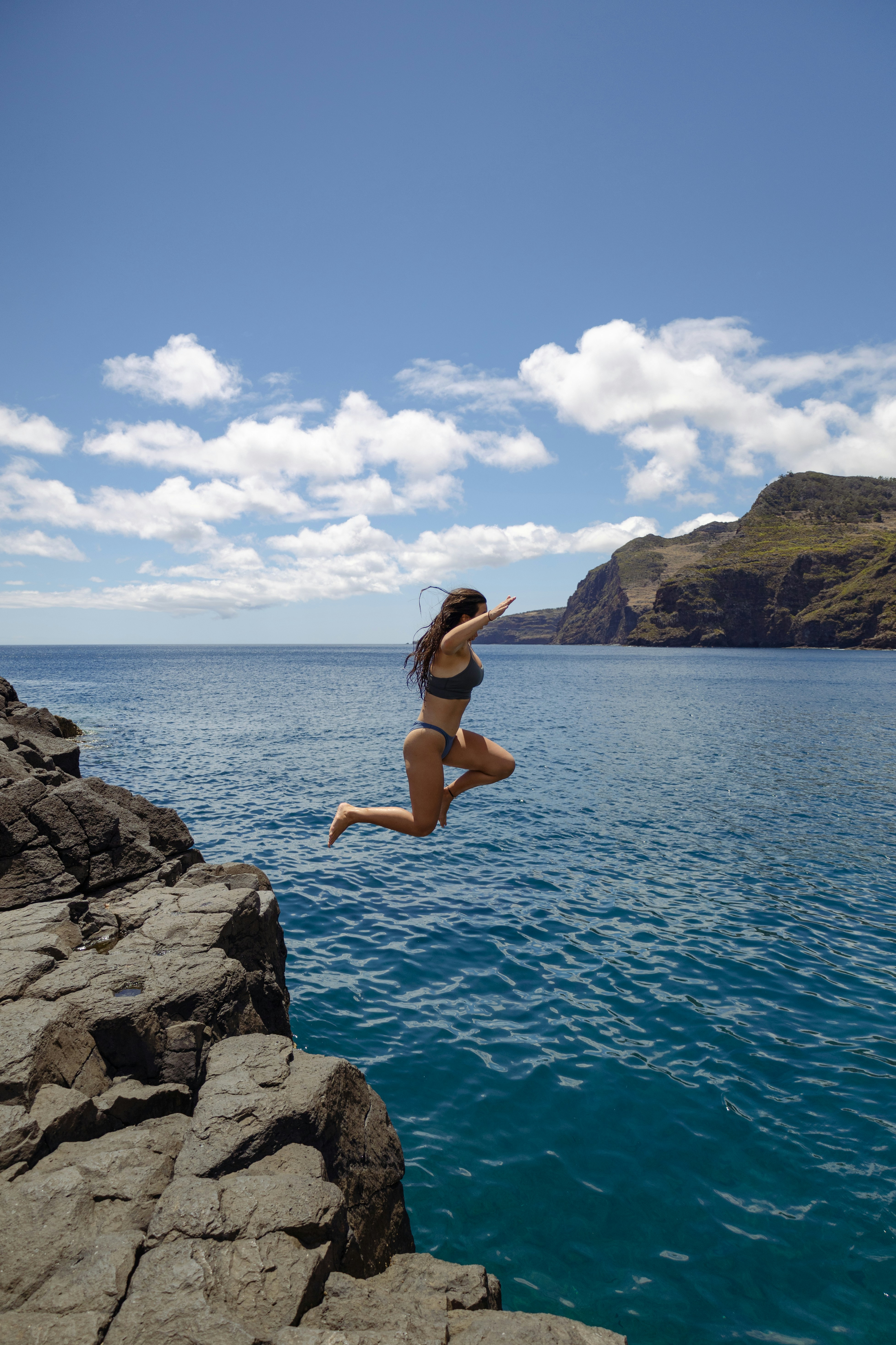 A woman jumping off a cliff into the ocean photo – Free Sunrise Image ...