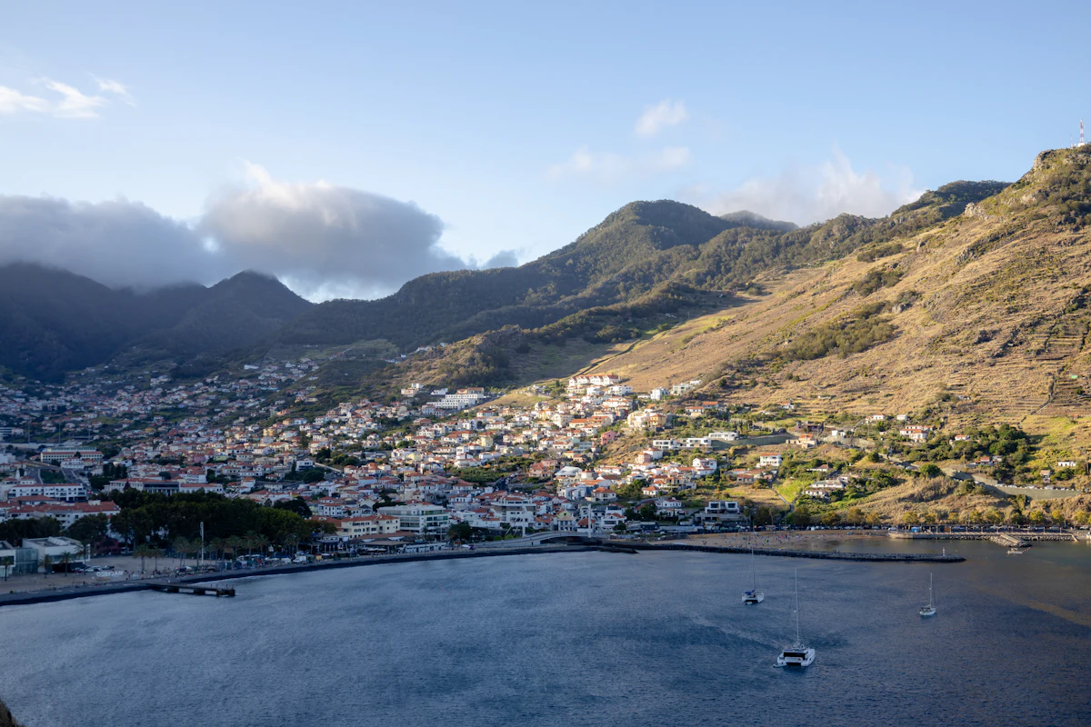 Machico and its bay in low sun, with houses climbing the valley into the hills