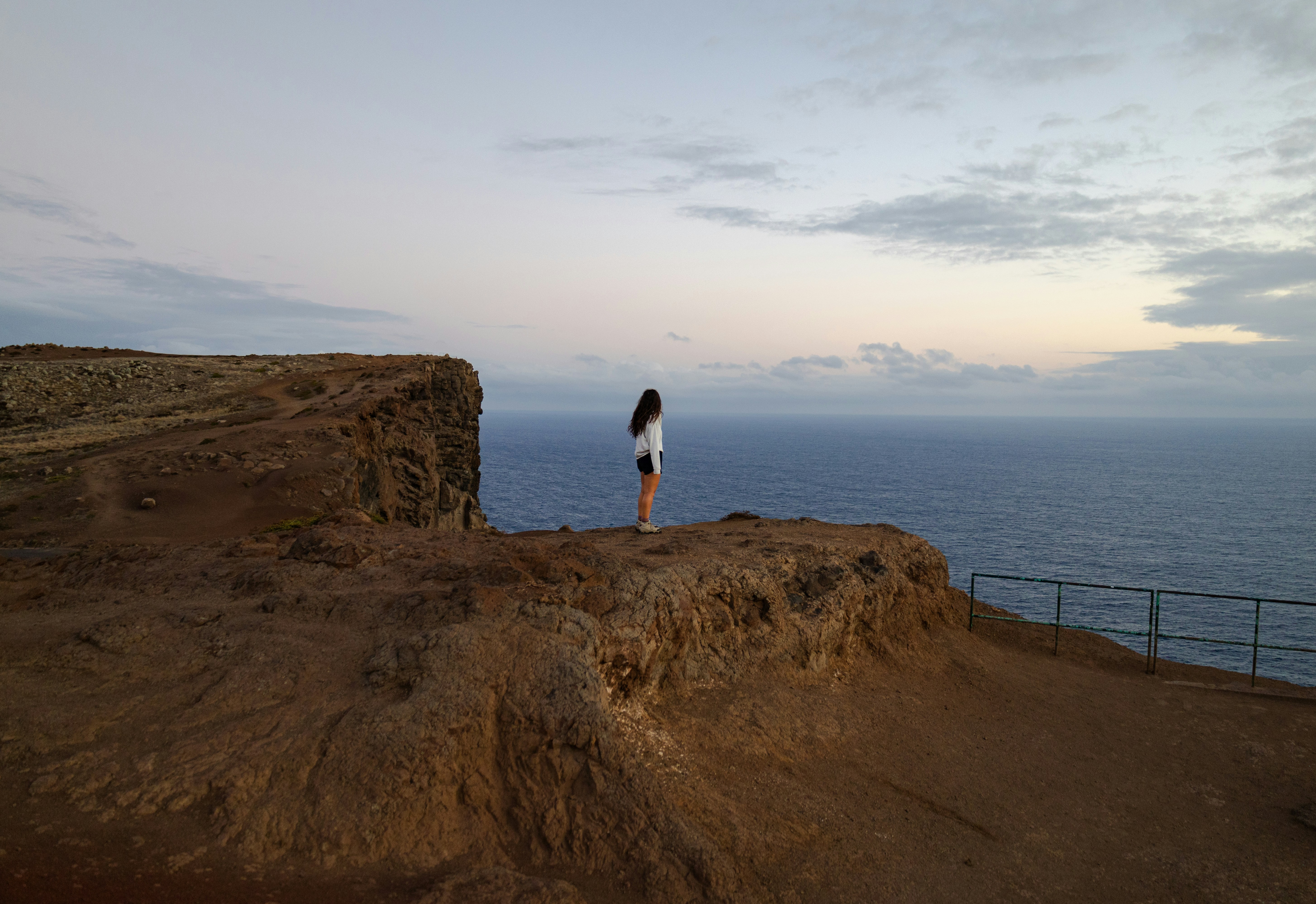 A person standing on a cliff overlooking the ocean photo – Free Ponta ...