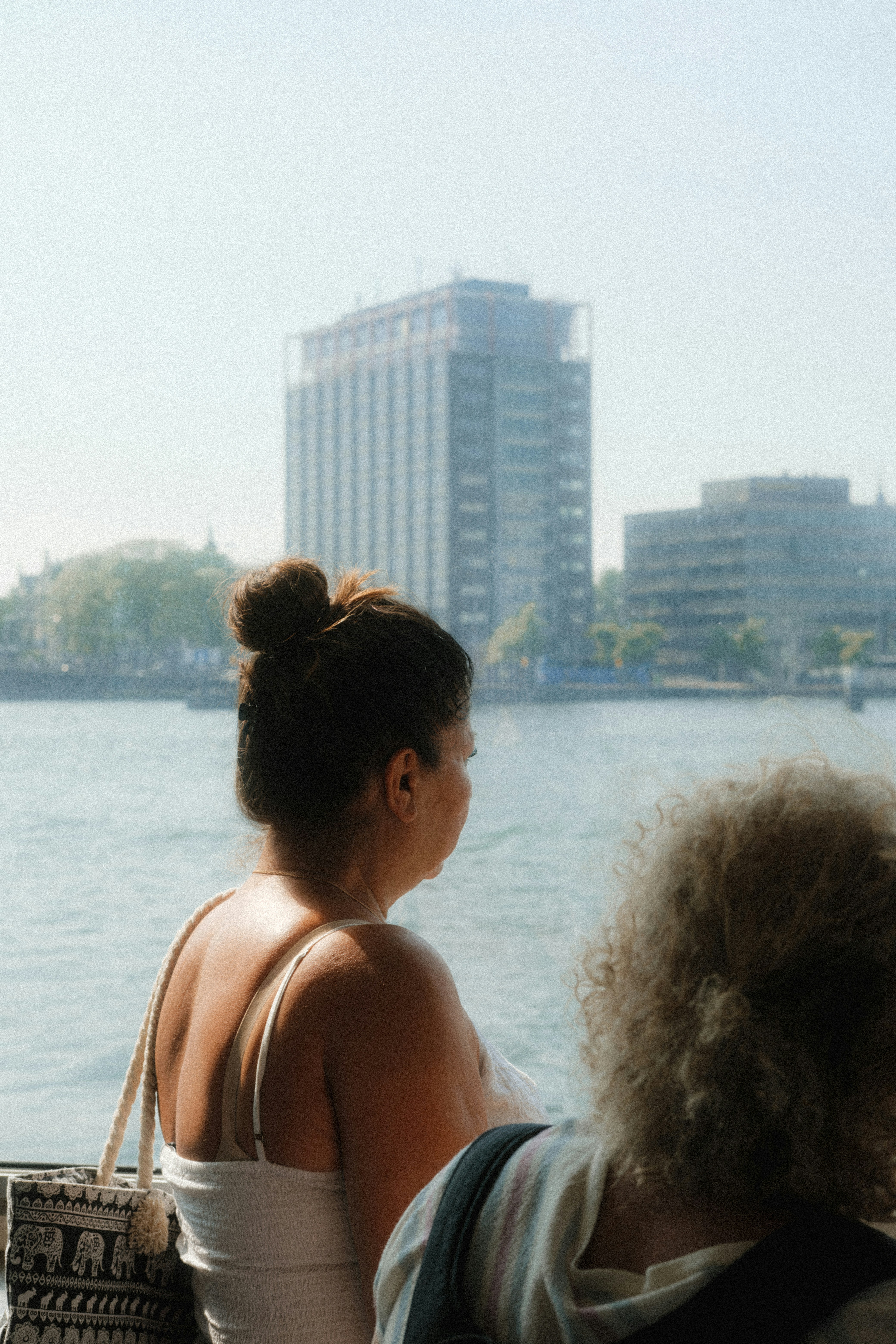 A couple of women sitting next to each other near a body of water
