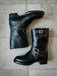 A pair of black boots sitting on top of a tiled floor