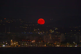 A red ball is in the sky over a city