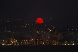 A red ball is in the sky over a city