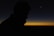 A silhouette of a person at sunset with the moon in the distance