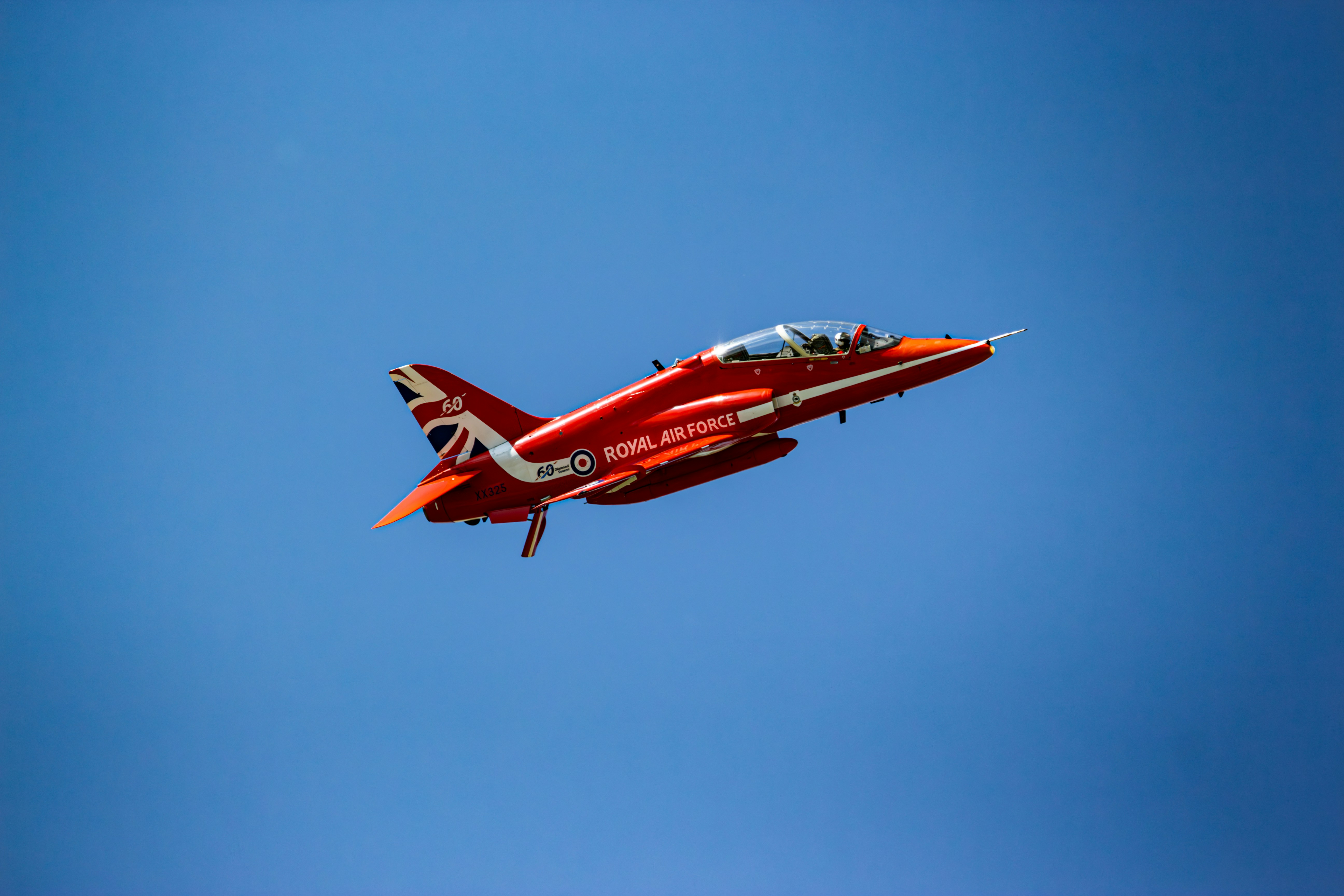 Ein rot-weißer Jet fliegt durch den blauen Himmel