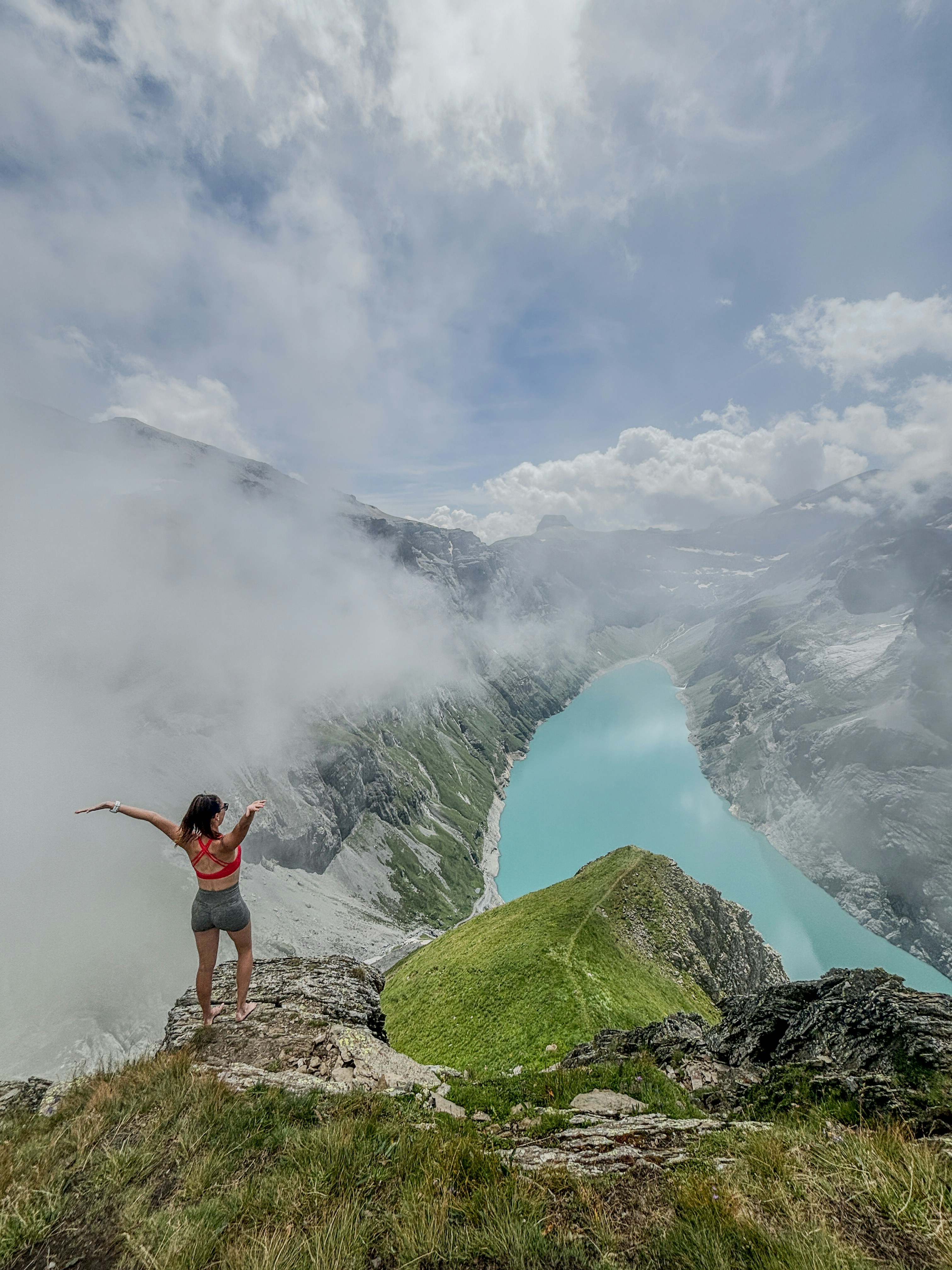 Une femme debout au sommet d’une montagne à côté d’un lac