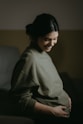A pregnant woman sitting on a couch smiling