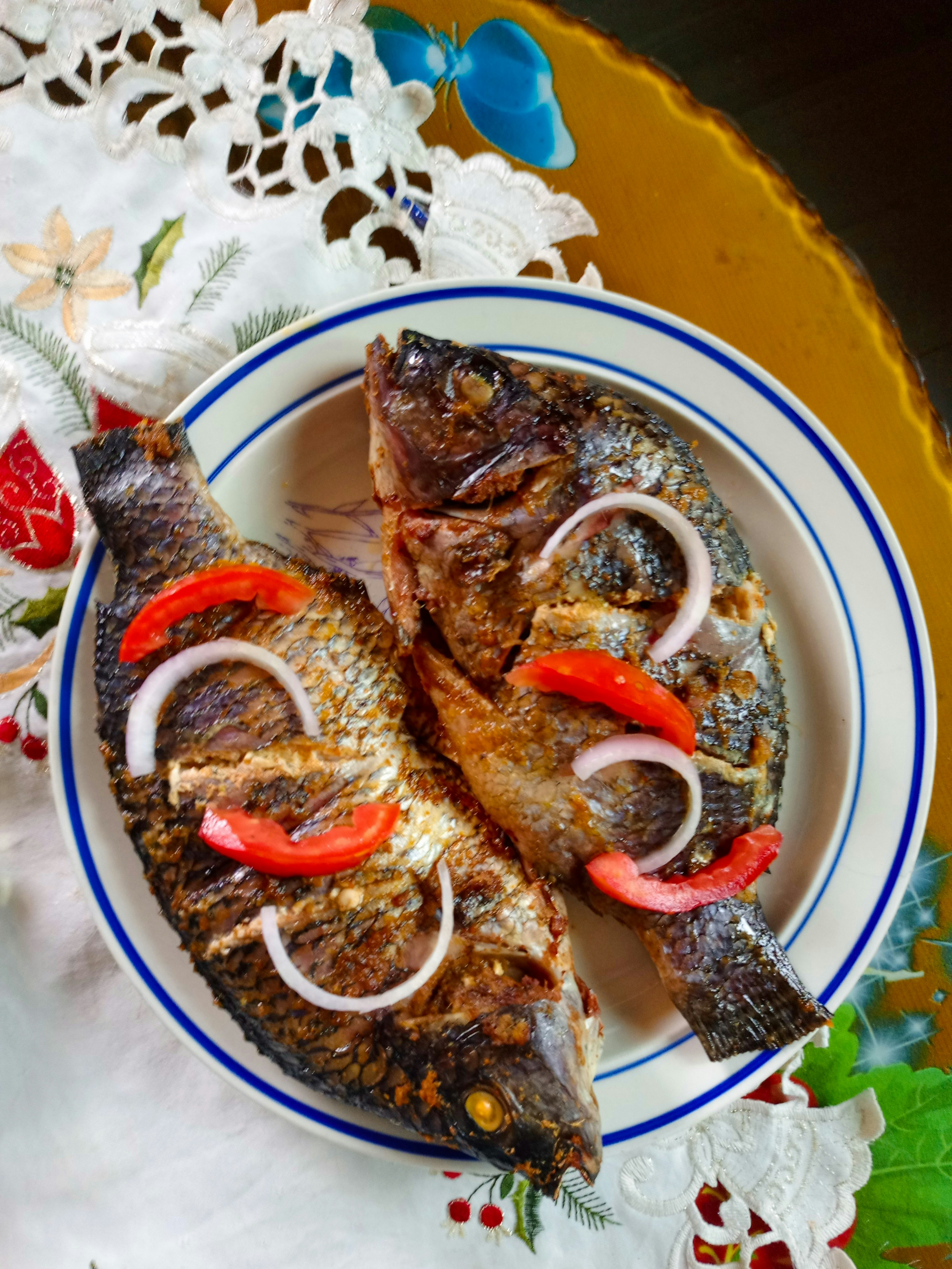Two fish on a plate with onions and peppers