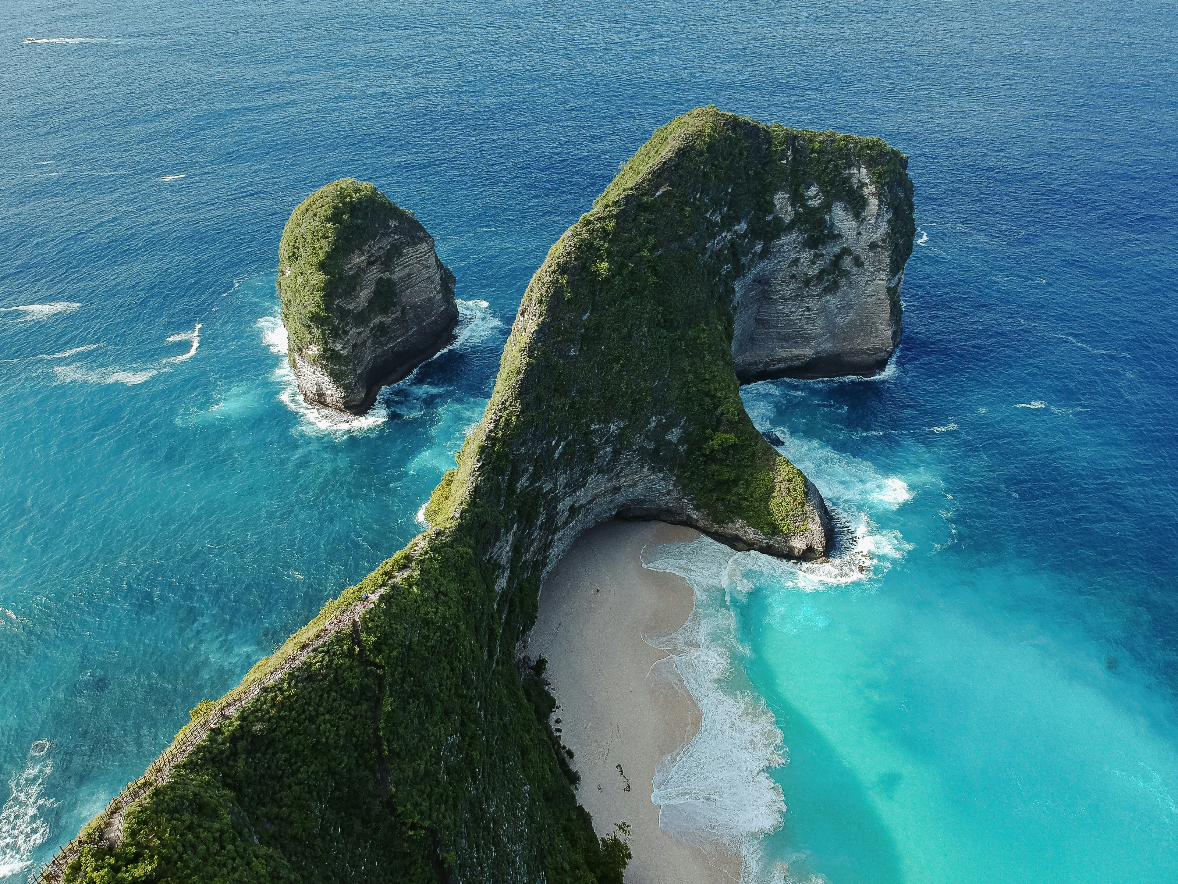 An aerial view of a beach with two large rocks sticking out of the water