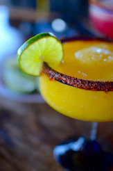 A yellow margarita with a lime slice on the rim