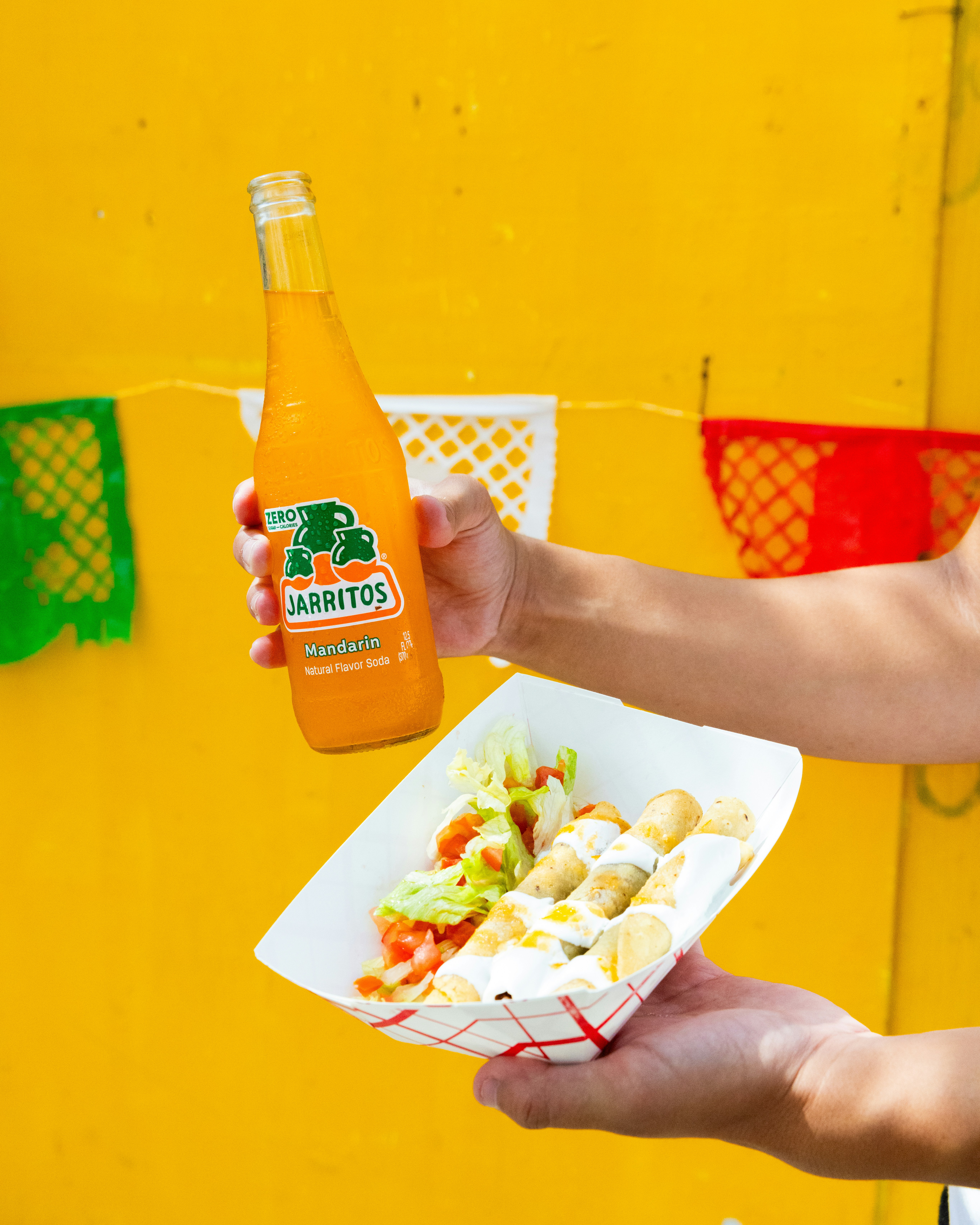 A person holding a bottle of orange juice and a plate of food